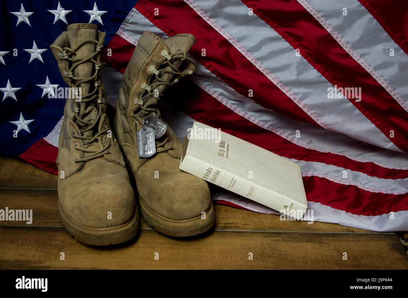 Flag with Bible, dog tags, and combat boots in remembrance of the fallen Stock Photo