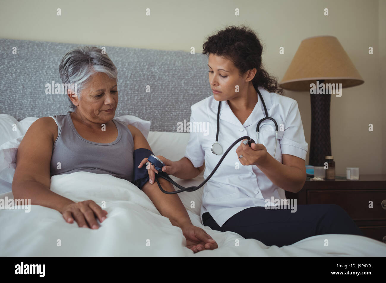 Female doctor measuring blood pressure of a senior woman at home Stock ...
