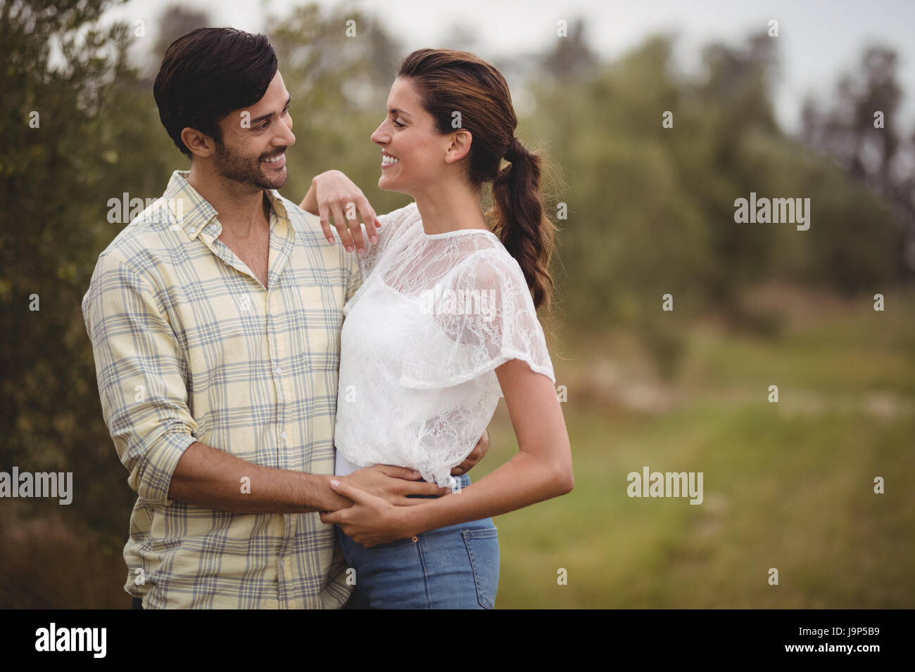 Happy young couple embracing at olive farm Stock Photo - Alamy