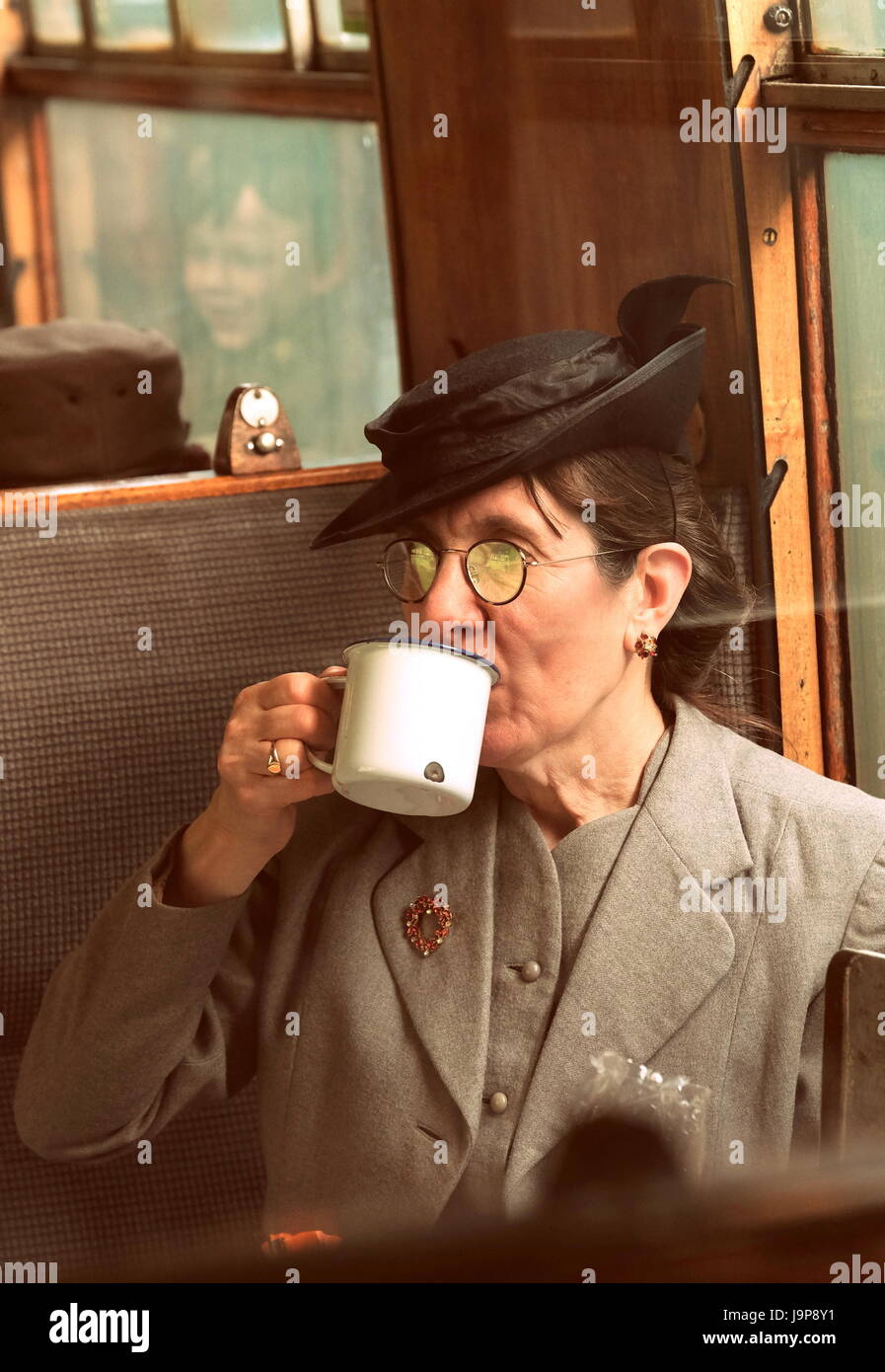 Woman drinking tea on the train at the Watercress Line War on the Line reenactment event , Mid Hants Railway, Hampshire England, uk Stock Photo