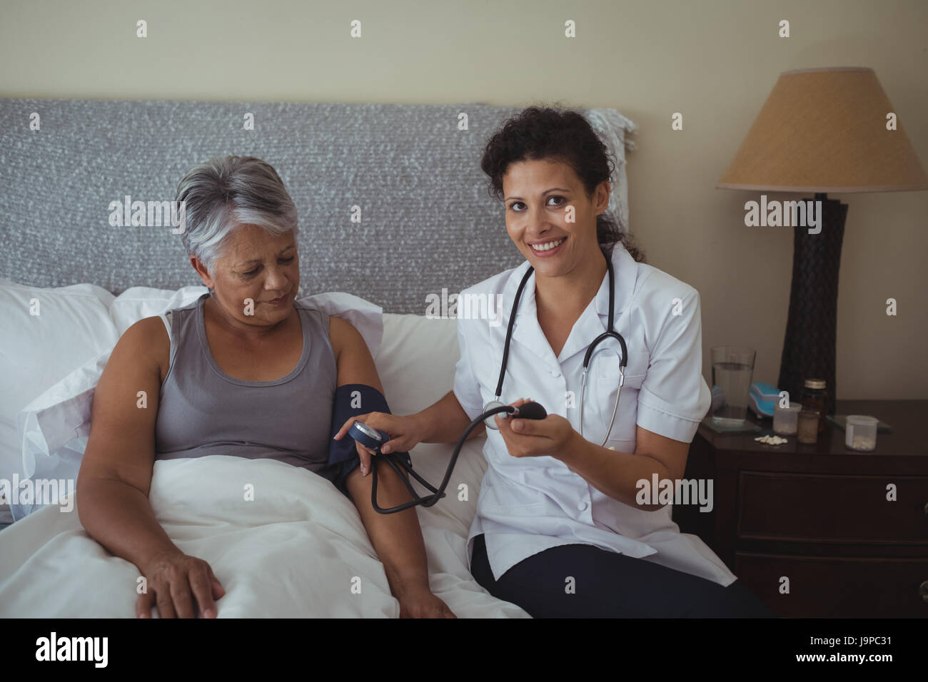 Female doctor measuring blood pressure of a senior woman at home Stock ...