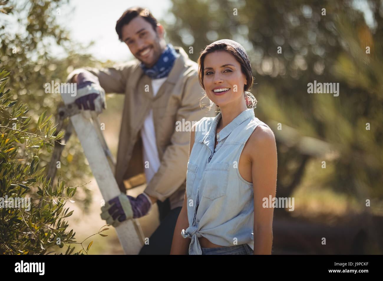 Portrait of happy young couple standing by trees at olive farm Stock ...