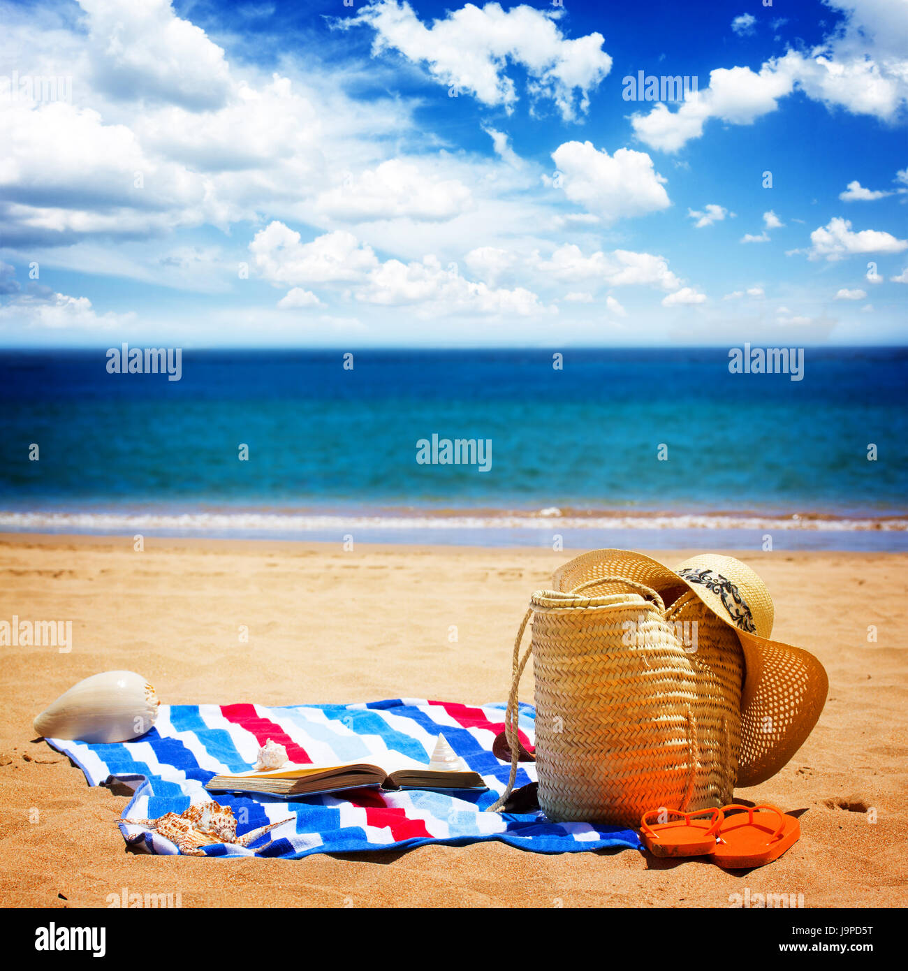 towel and sunbathing accessories on sandy beach by the sea, retro toned ...