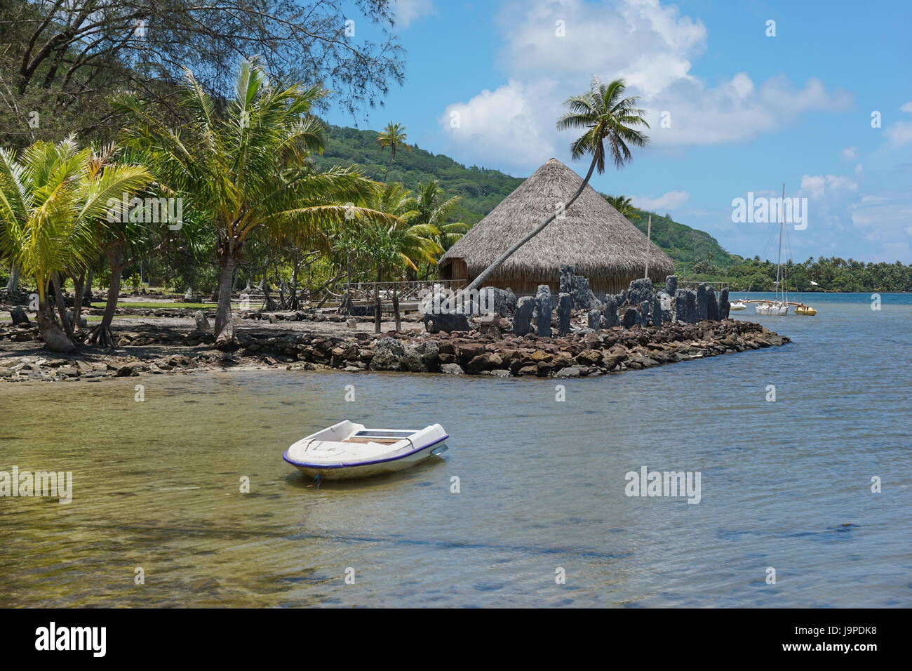Coastal landscape on the shore of the saltwater lake Fauna Nui with a marae and a traditional hut, Huahine island in French Polynesia, south Pacific Stock Photo