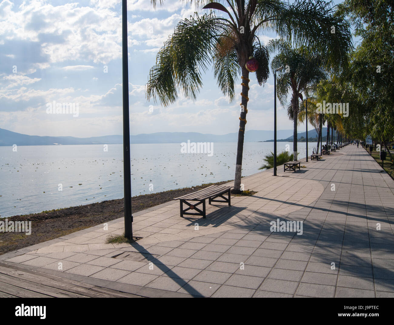 A bench on a nice promenade on lake Chapala. Lake and hills in the background. Stock Photo