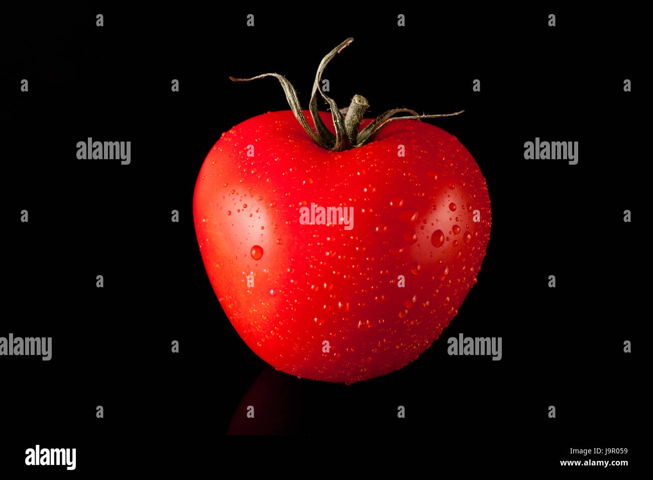 Single Red Tomato on black background Stock Photo - Alamy