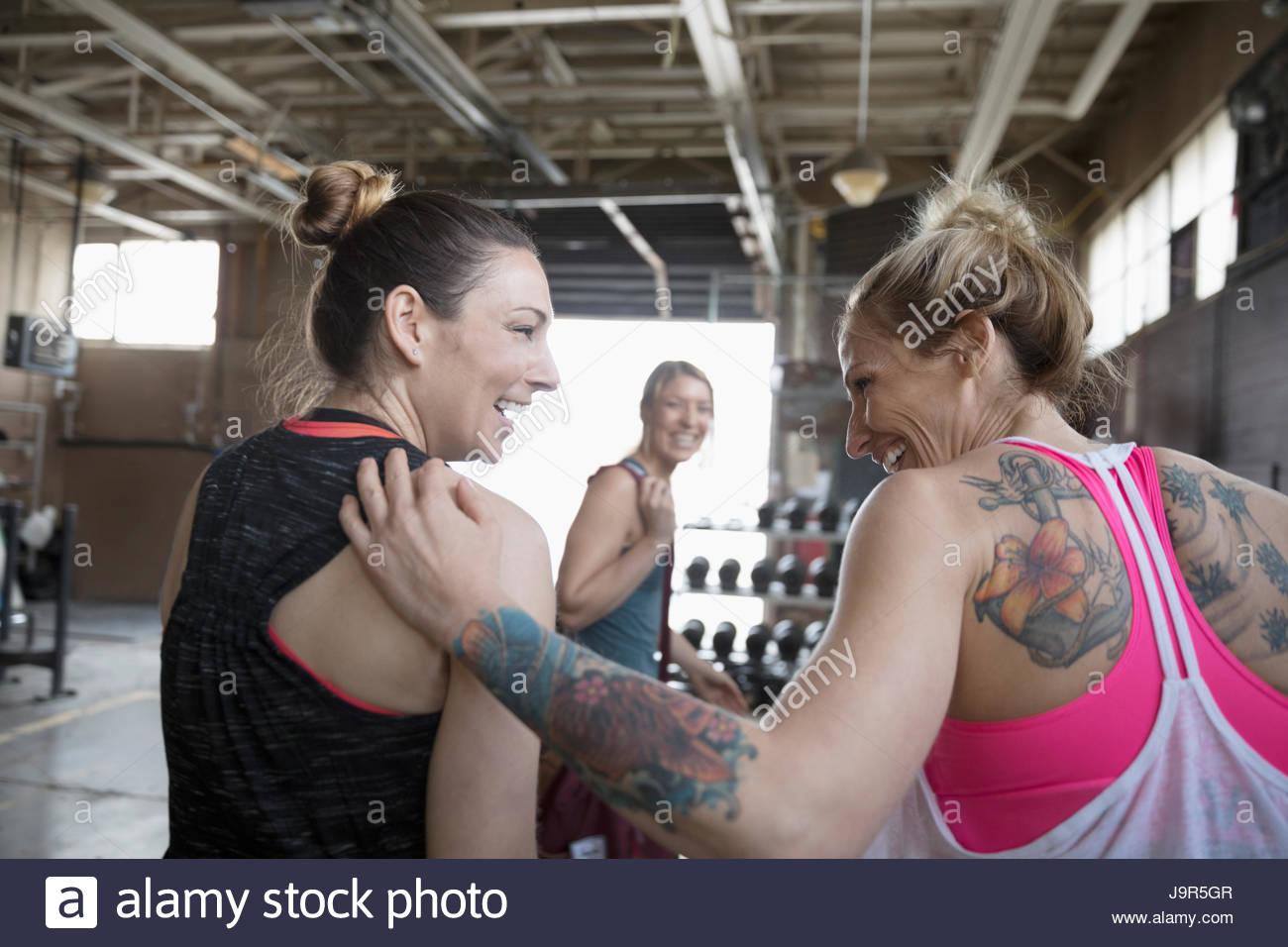 Strong, tattooed women smiling in gym Stock Photo