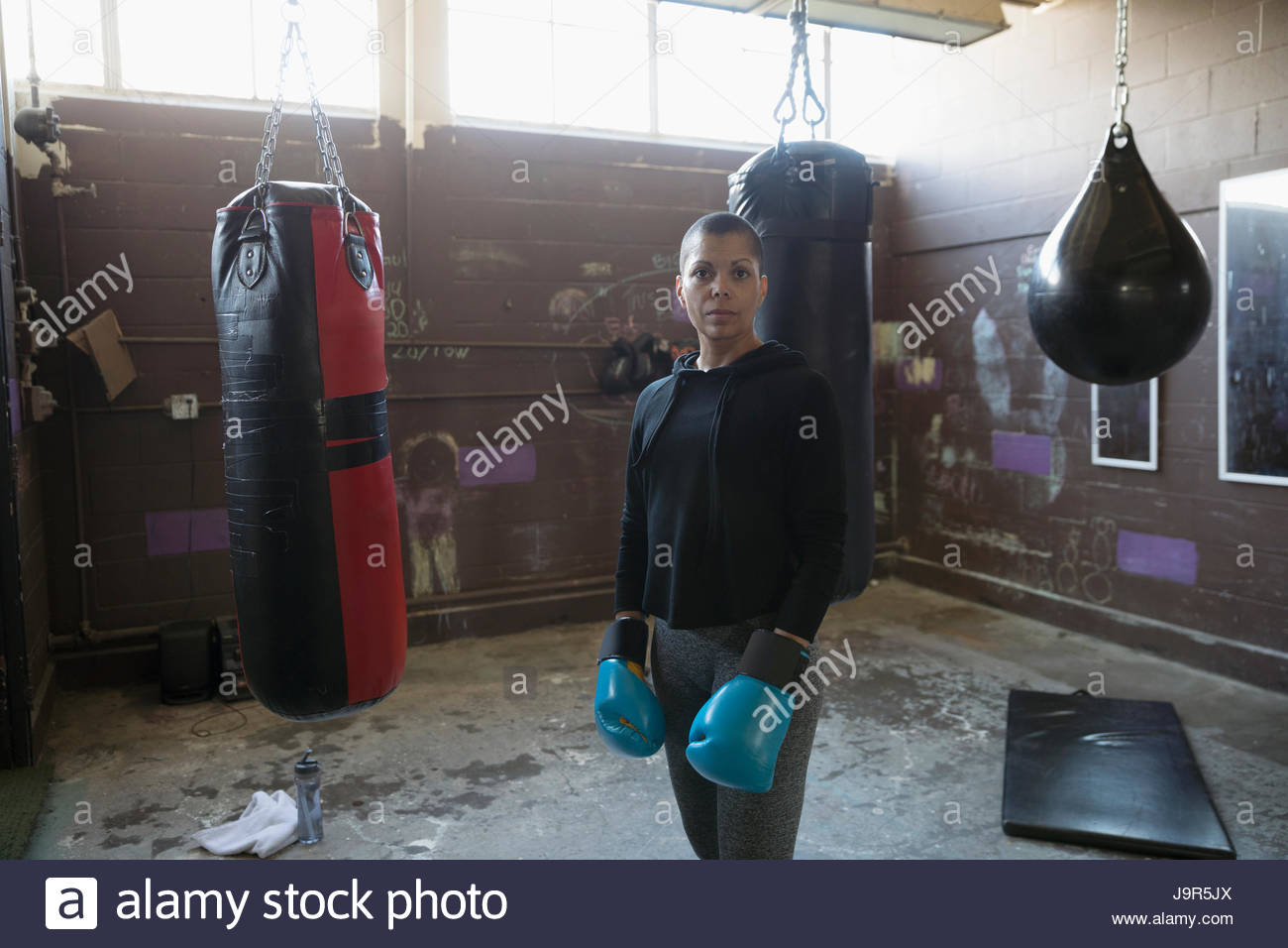 Portrait confident, tough female boxer in boxing gloves near punching