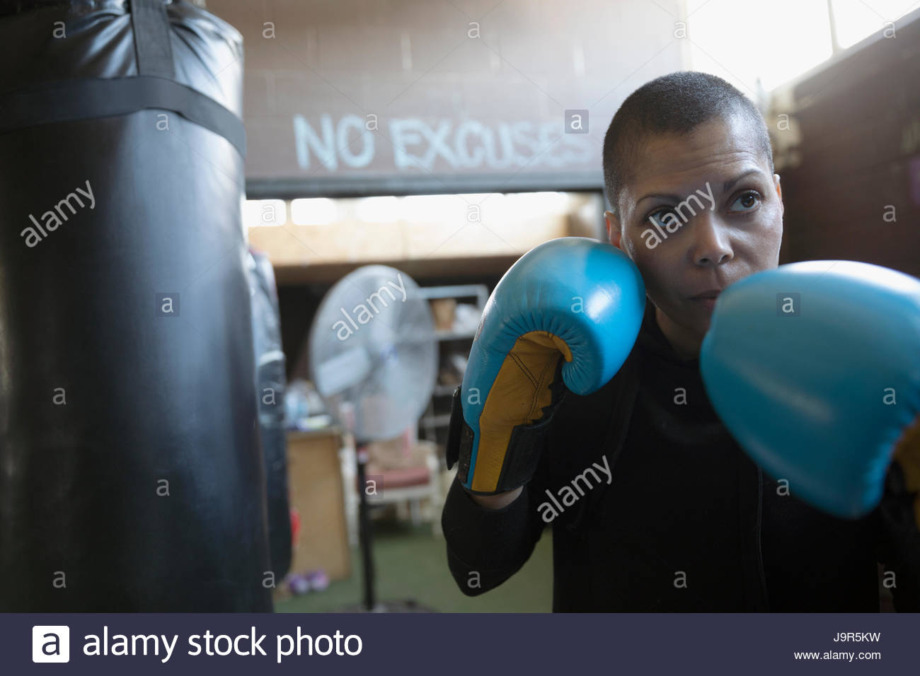 Portrait serious, tough female boxer in boxing gloves in fighting
