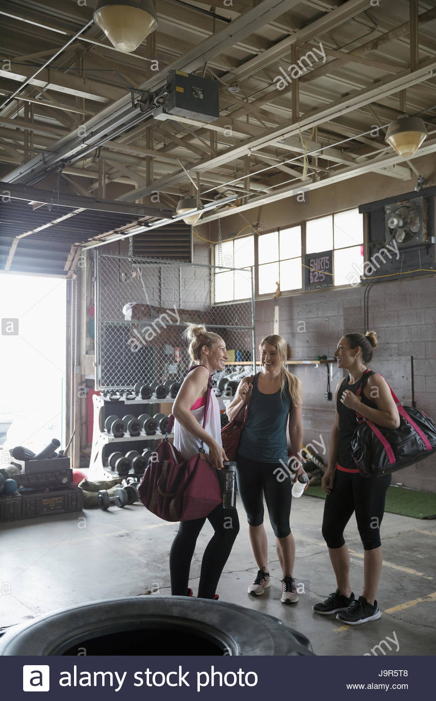 Women with gym bags talking in gritty gym Stock Photo
