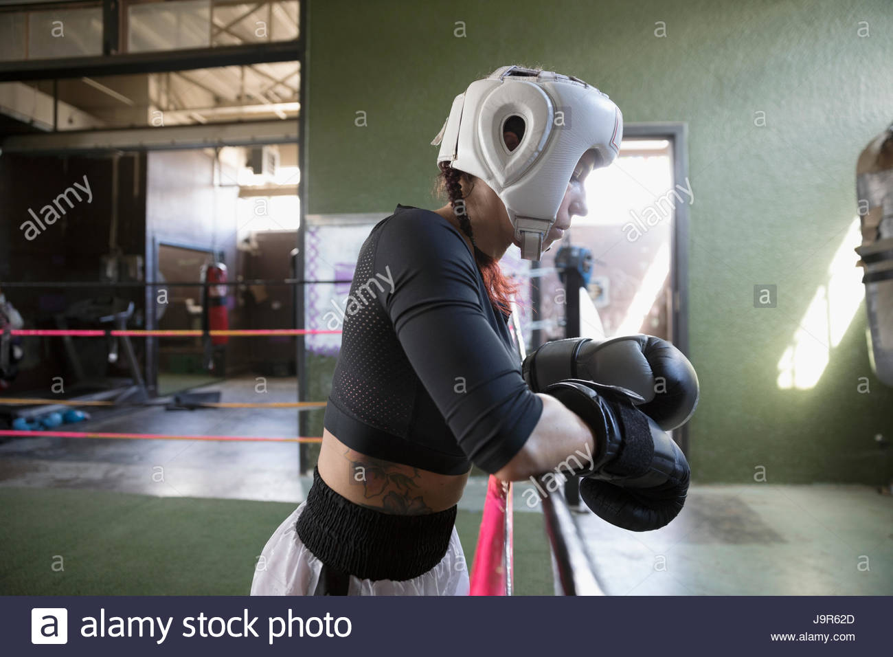 Strong, tough female boxer in protective headwear and boxing gloves