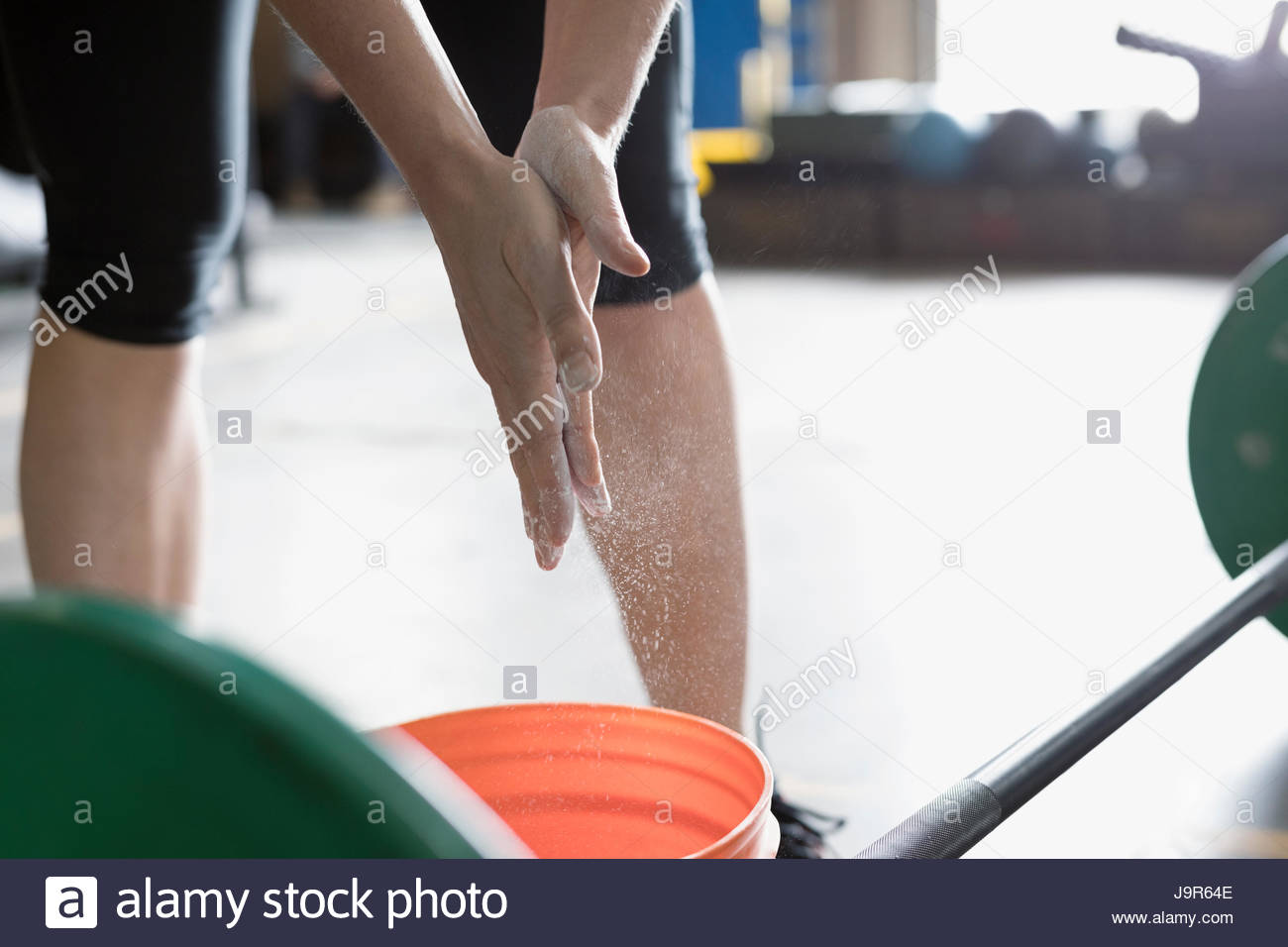 Close up woman weightlifting, chalking hands at barbell in gym Stock