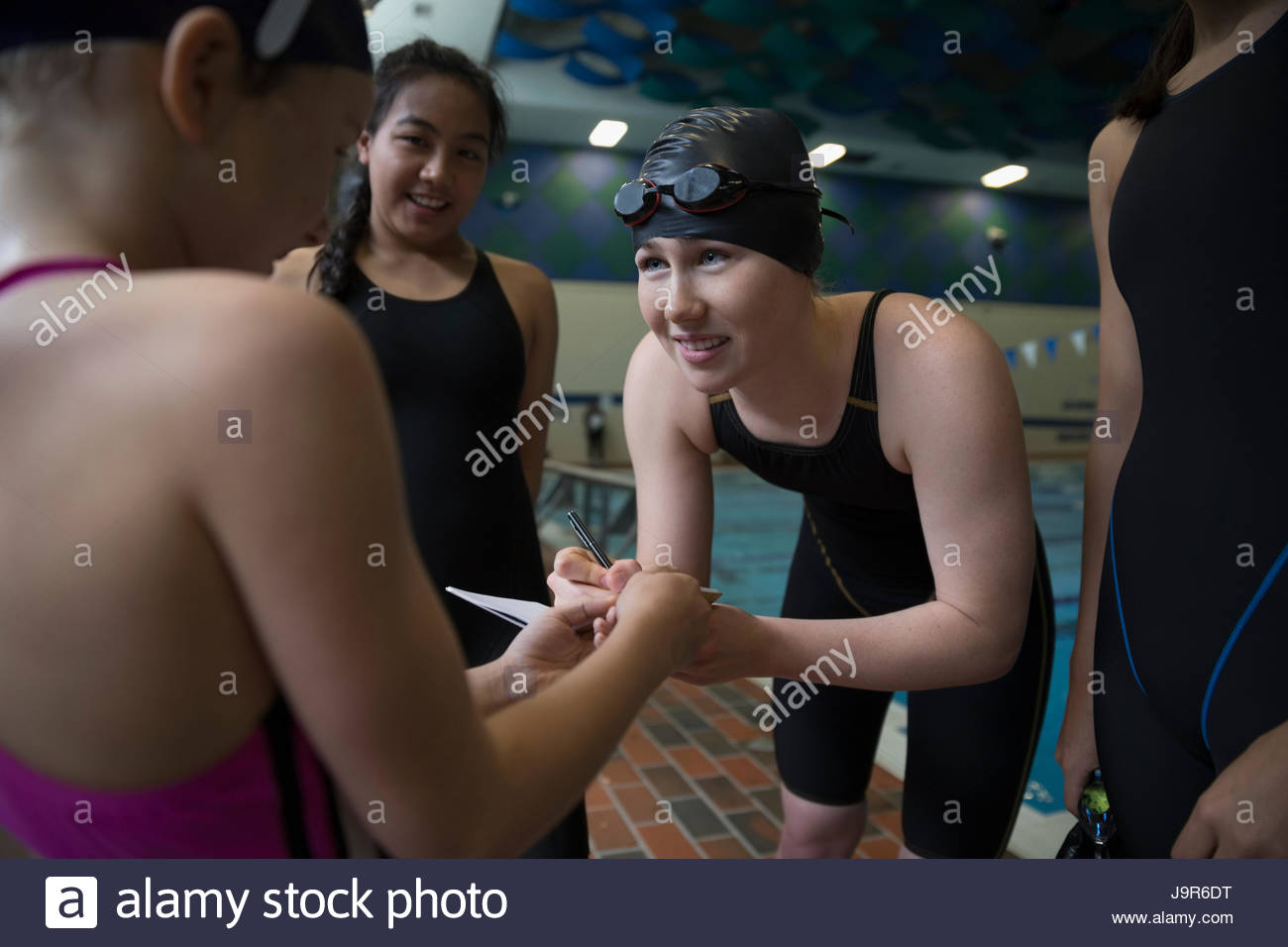 Female swimmer signing autograph for girl at swimming pool Stock Photo