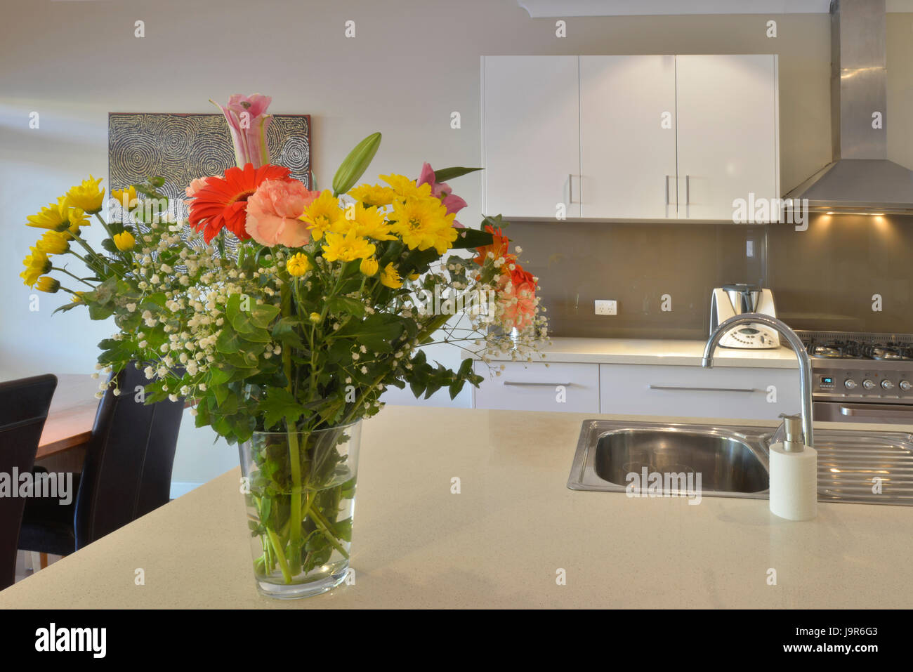 Modern Australian kitchen, with clean surfaces and vase of flowers. Stock Photo