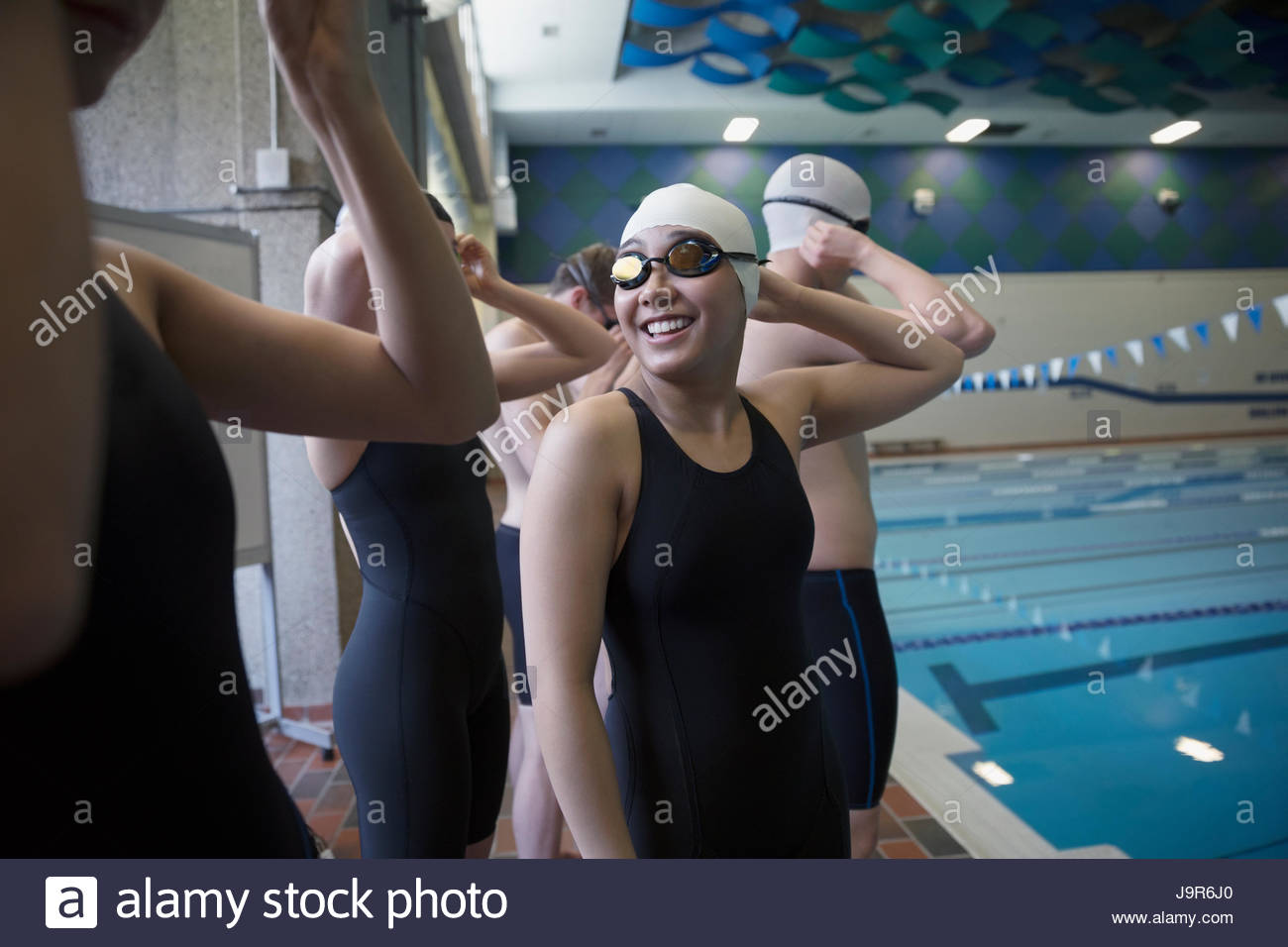 Smiling teenage girl swimmer talking to teammate at swimming pool Stock Photo