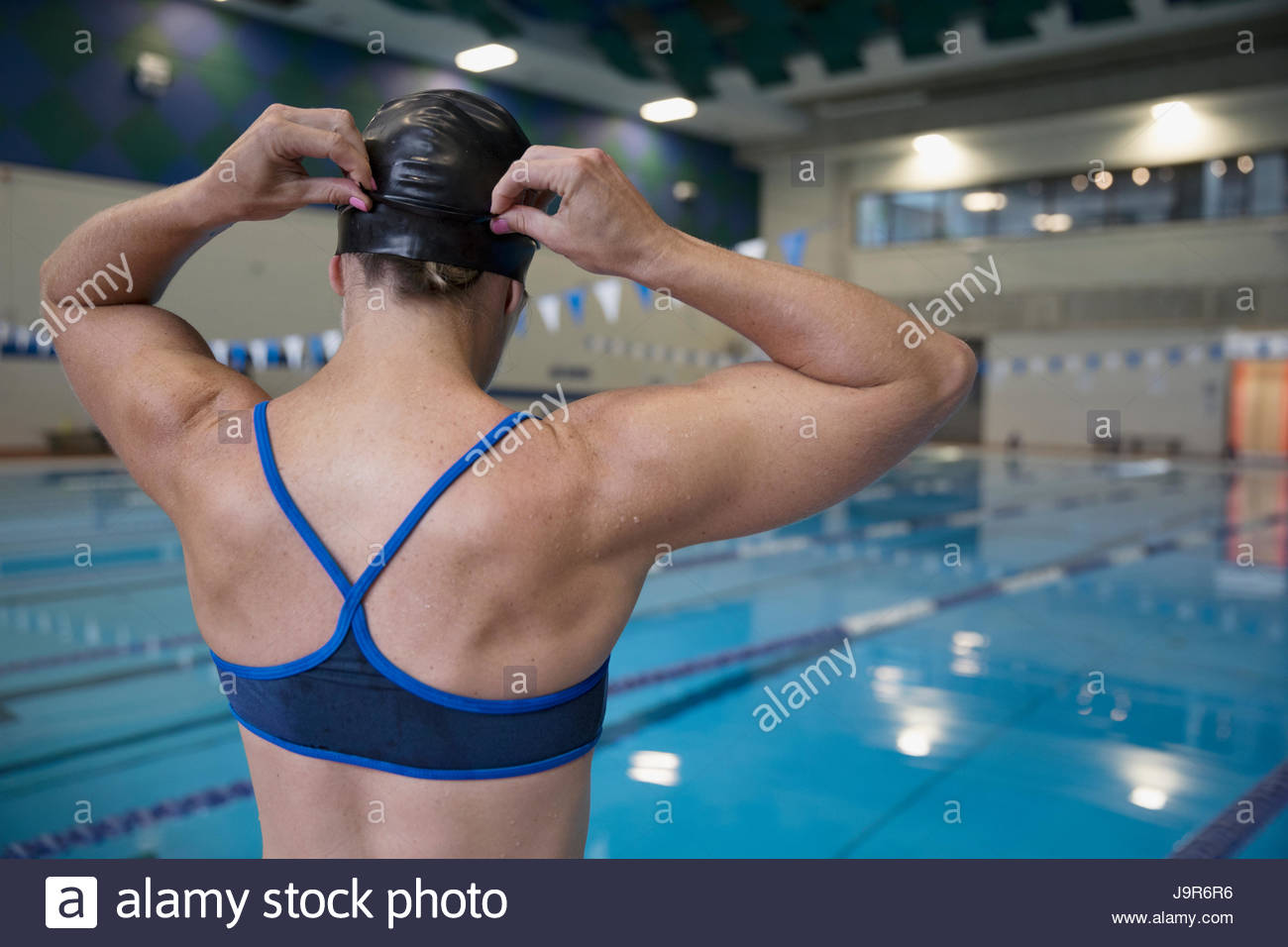 Rear view female swimmer adjusting swimming cap at swimming pool Stock Photo
