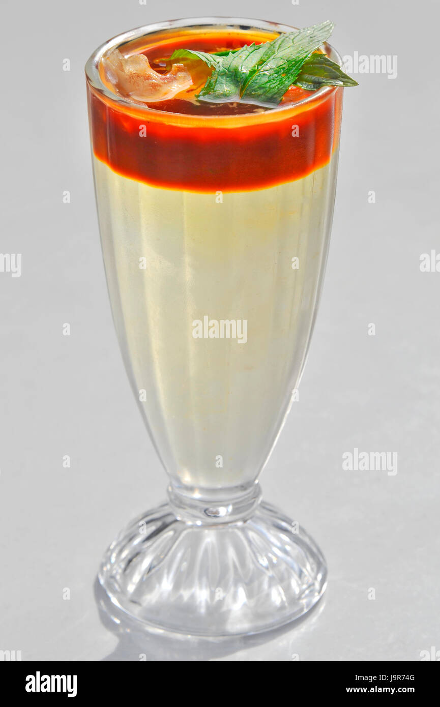 Tall glass with a pale cocktail. Red Tomato juice at rim with green leaf Stock Photo