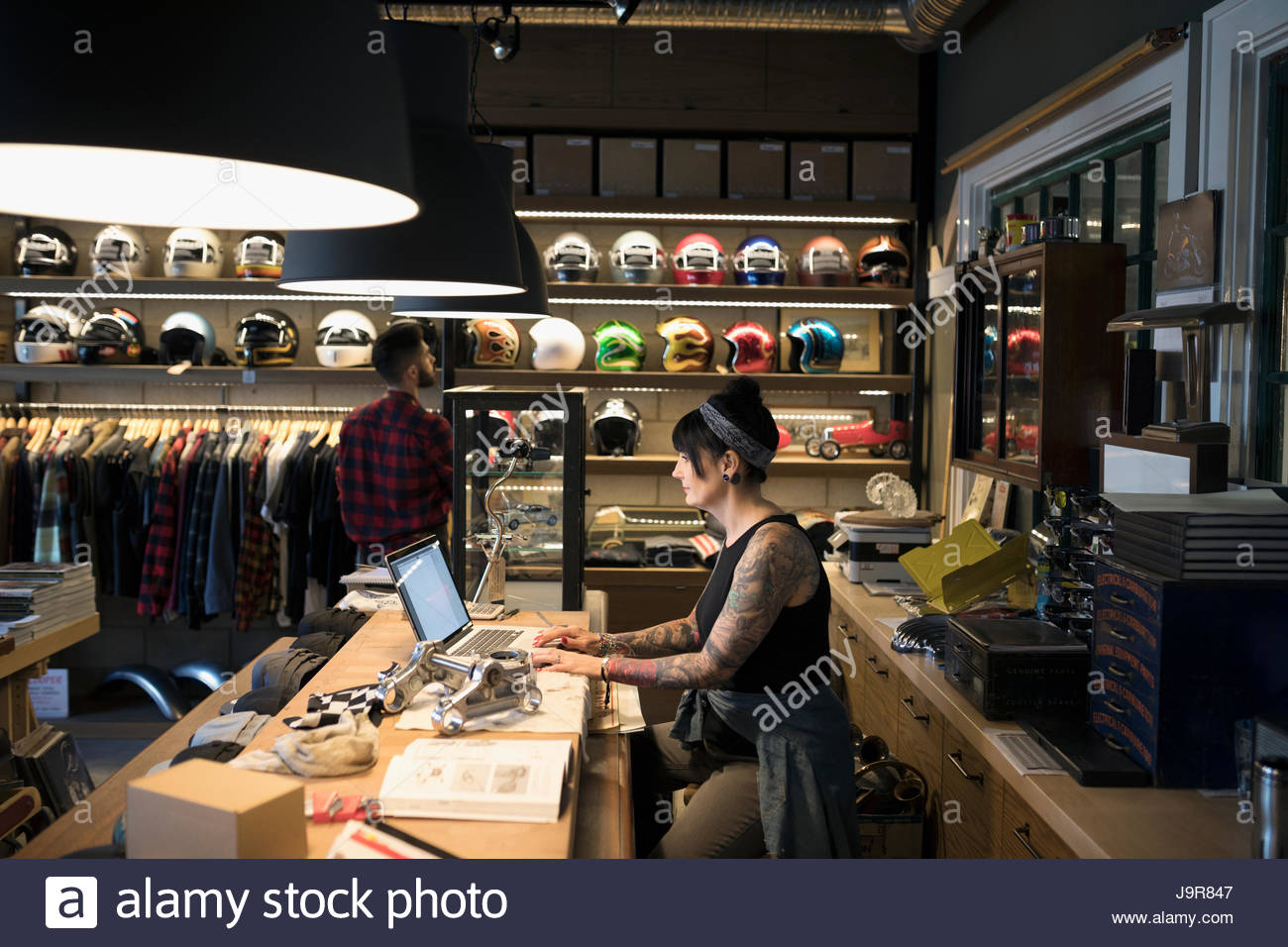 Female motorcycle mechanic shop owner working at laptop behind counter