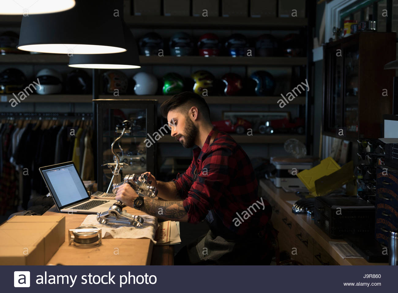 Motorcycle mechanic shop owner fixing part, working late behind counter