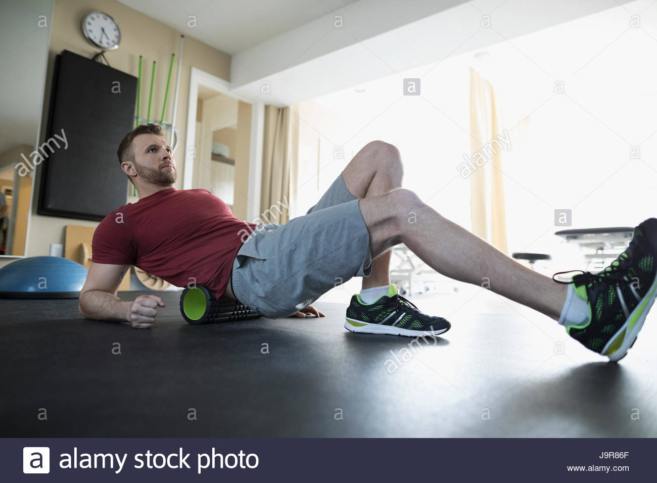 Man stretching back on roller in physiology clinic gym Stock Photo