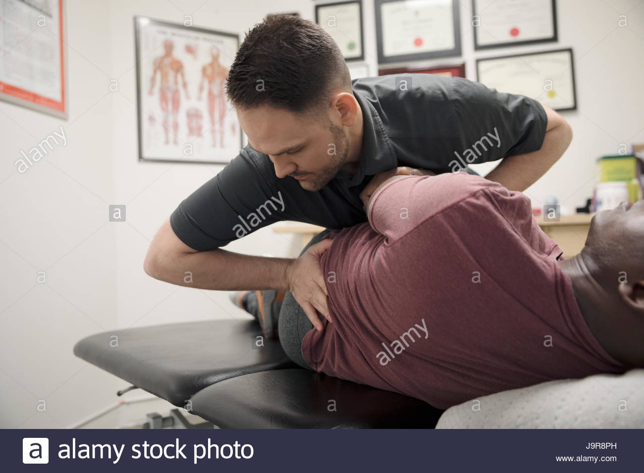 Male physiotherapist stretching client in office Stock Photo