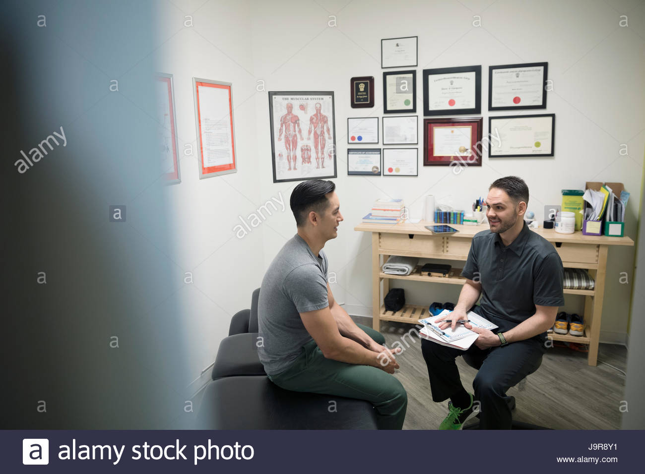 Male physiotherapist talking with client in office Stock Photo