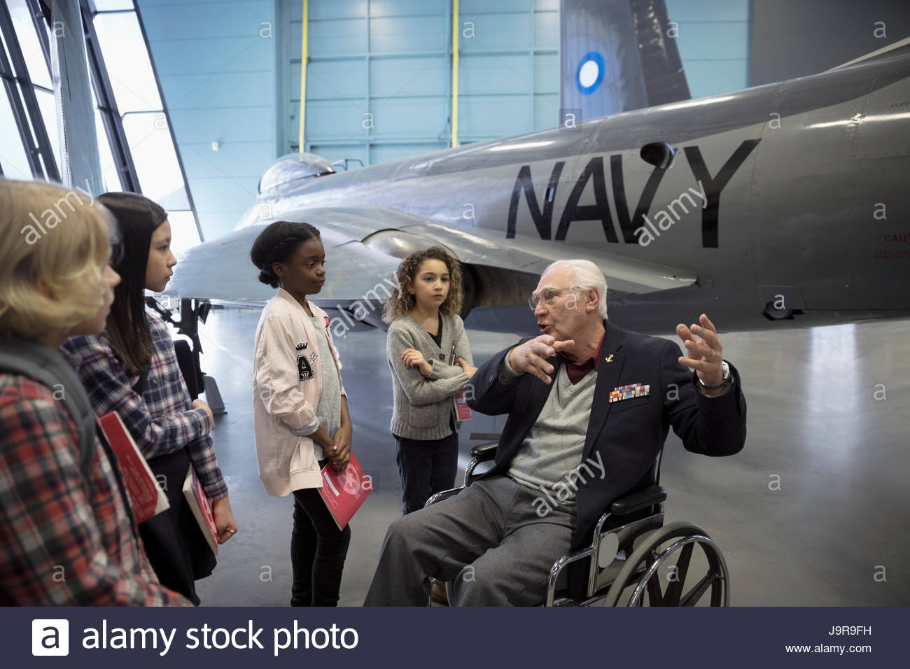 War veteran in wheelchair talking to students on field trip at Naval