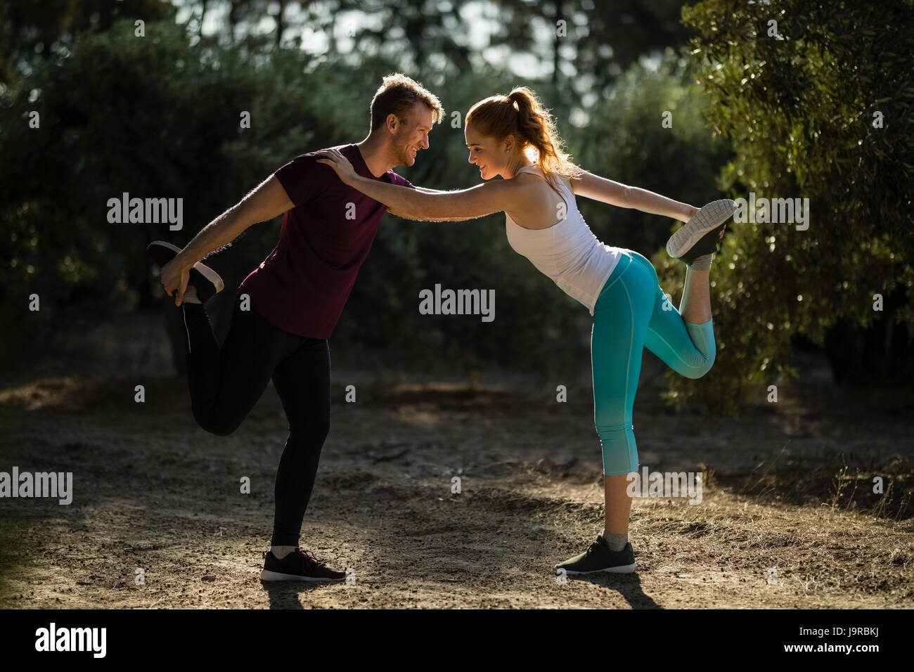 Full length of young man and woman exercising on field at farm during sunny day Stock Photo