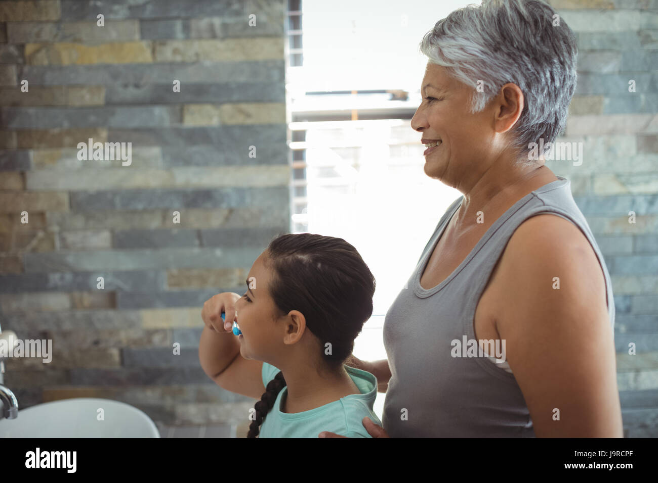 Grandmother and granddaughter brushing teeth in the bathroom at home Stock Photo