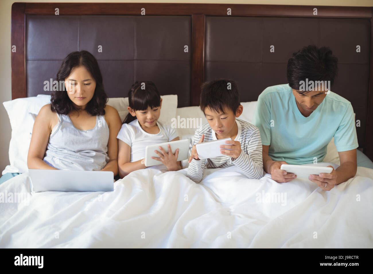 Family using electronic devices in bedroom at home Stock Photo Alamy