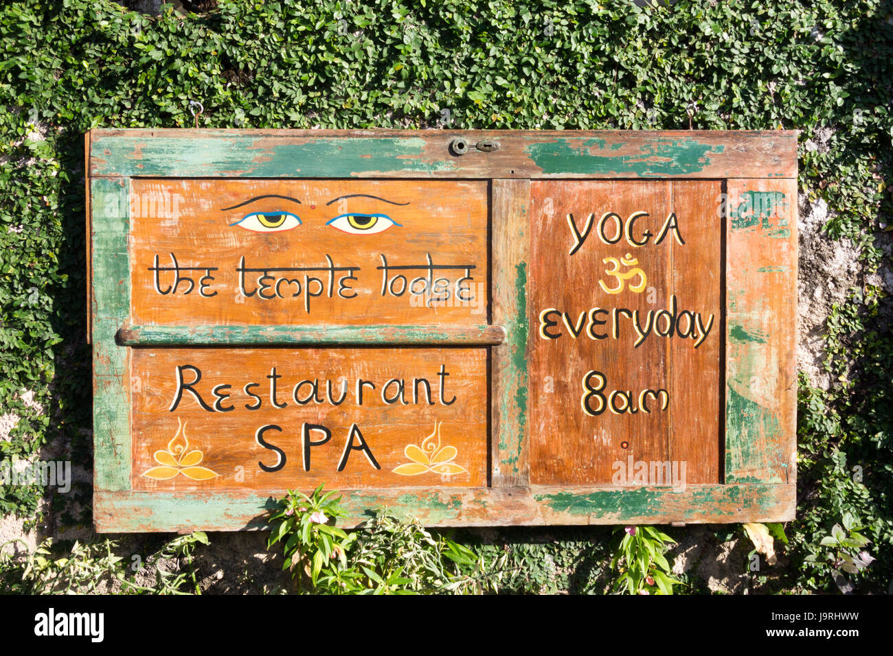 Sign on wall advertising the Temple Lodge restaurant and spa with yoga everyday, Bingin Beach, Bali, Indonesia Stock Photo