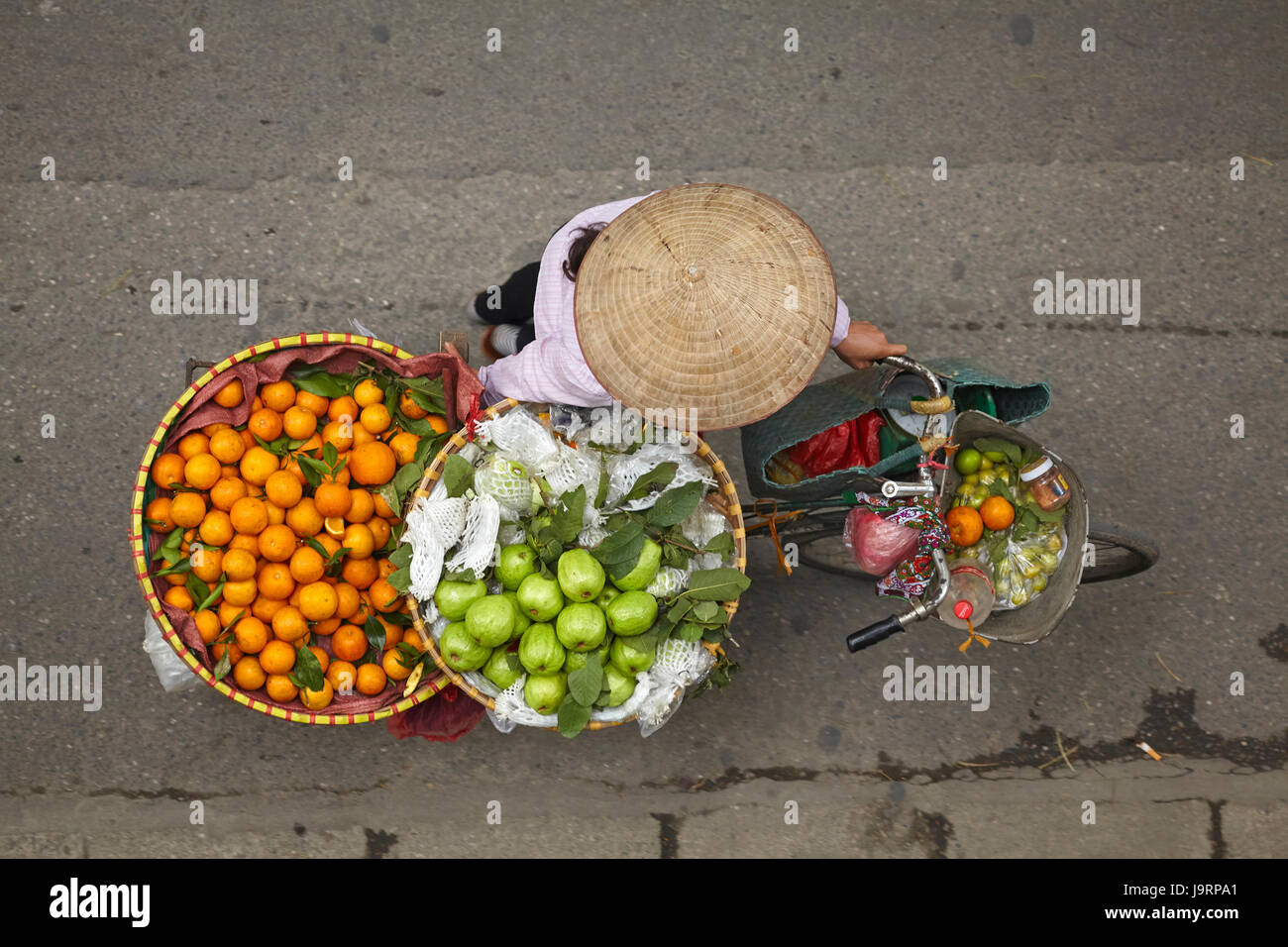 Street vendor with round baskets of fruit on bicycle, Old Quarter, Hanoi, Vietnam Stock Photo