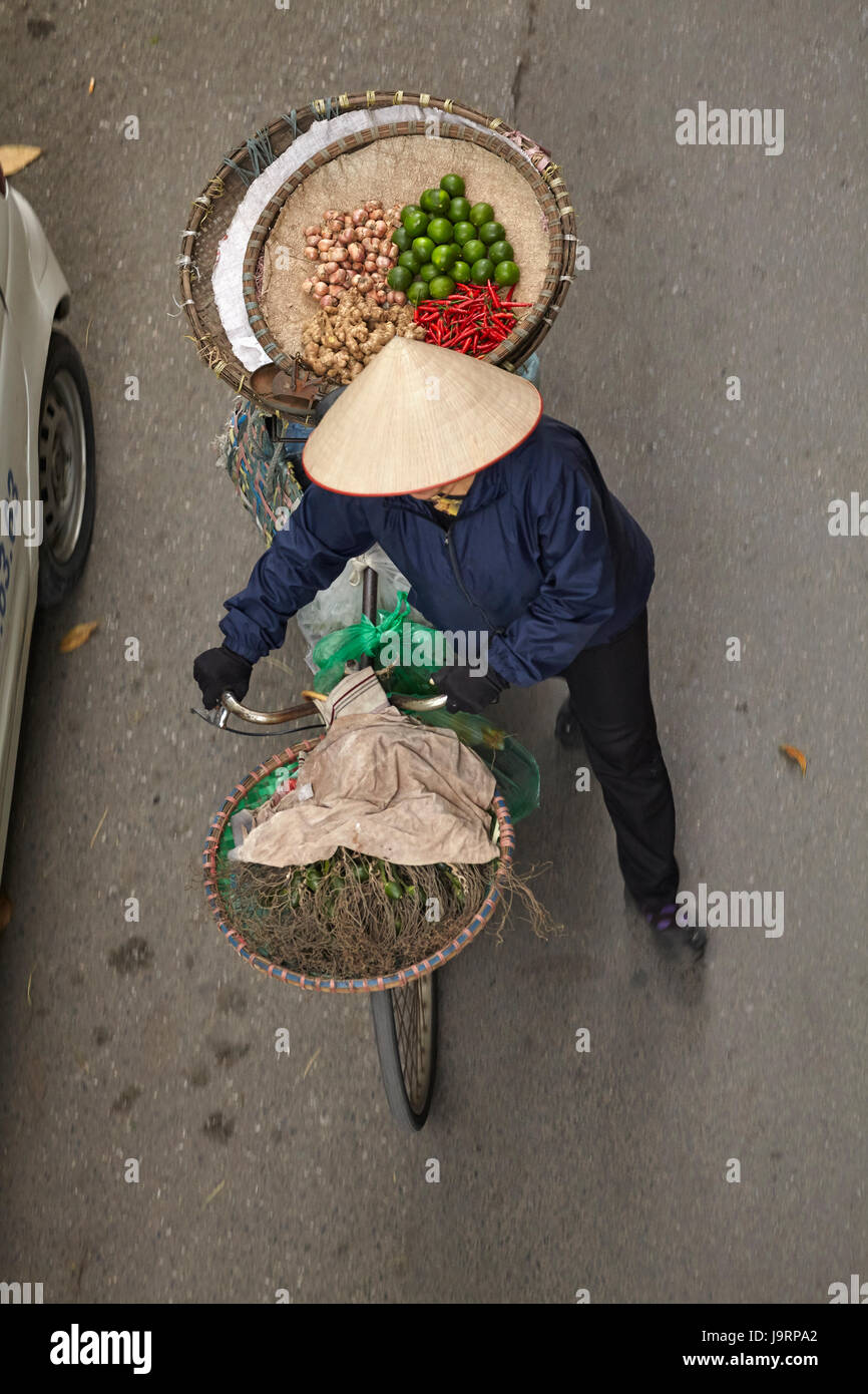 Street vendor with round baskets of fruit and vegetables on bicycle, Old Quarter, Hanoi, Vietnam Stock Photo