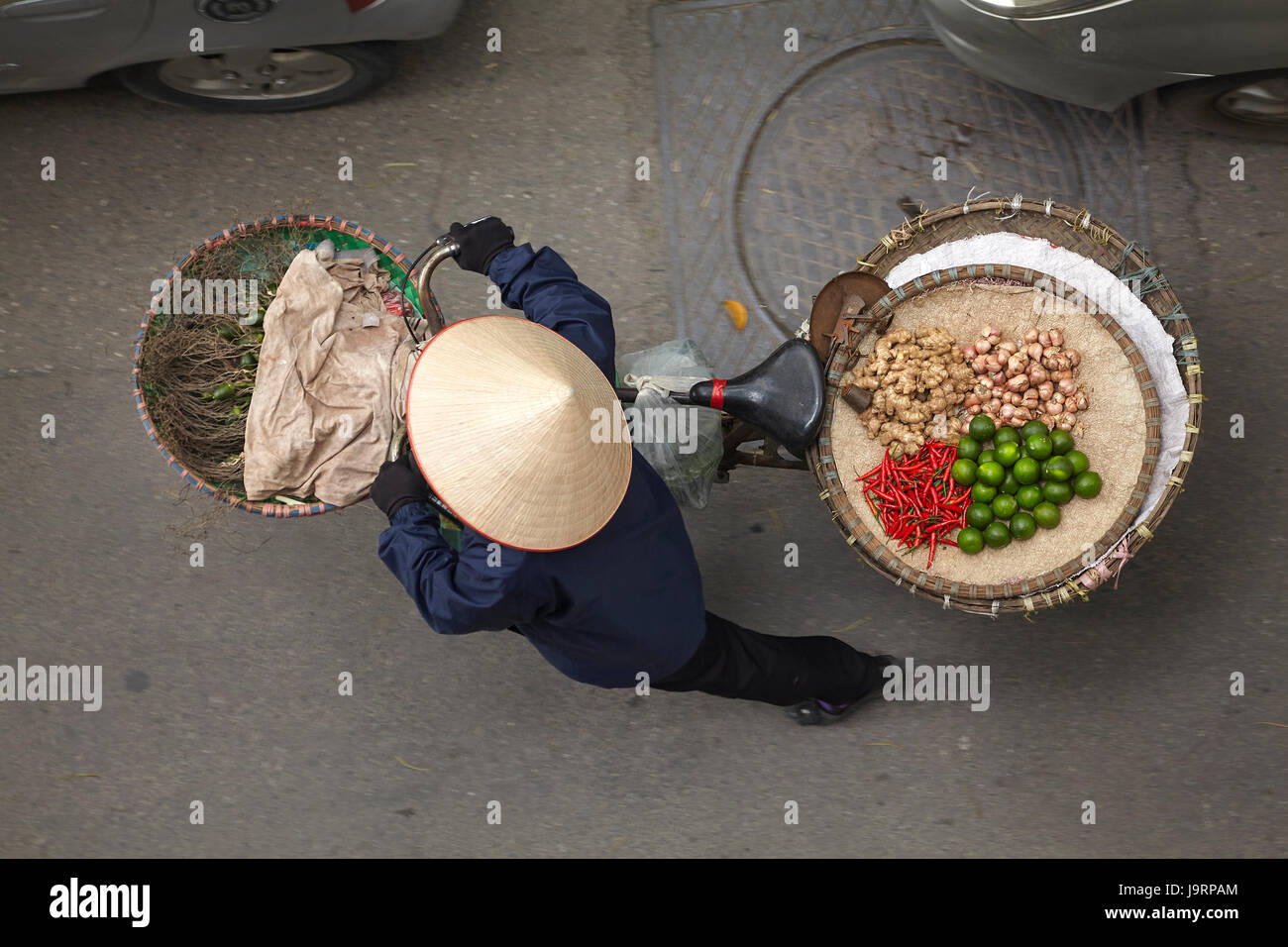 Street vendor with round baskets of fruit and vegetables on bicycle, Old Quarter, Hanoi, Vietnam Stock Photo