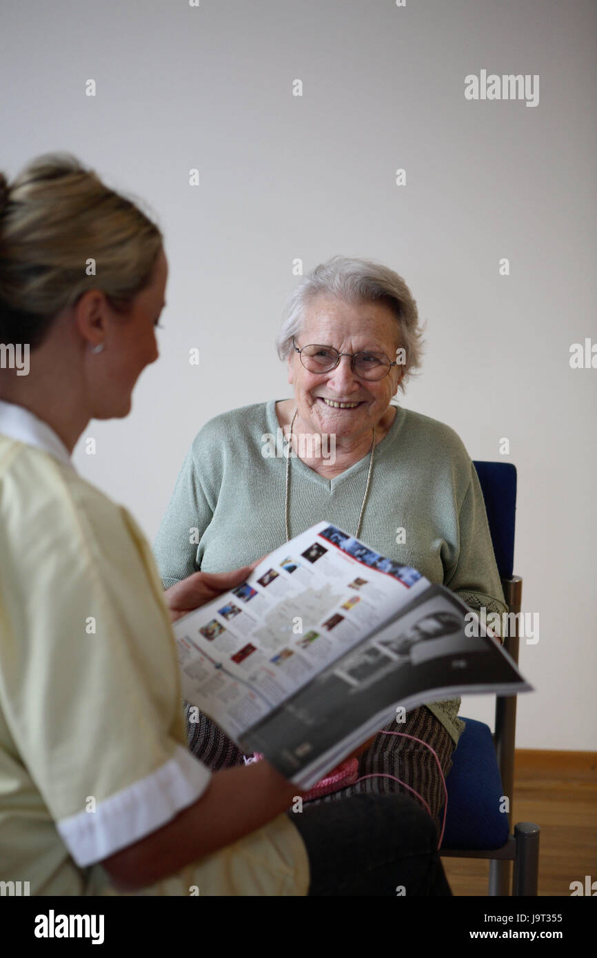 Old people's home,senior,smile,read out nurse,magazine,detail,nursing home for the elderly,person,look after,care,retirement home,glasses,old care,old person,loneliness,old age,socially,social contact,happily,happily,inside,two,senior citizens,women,occupation, Stock Photo