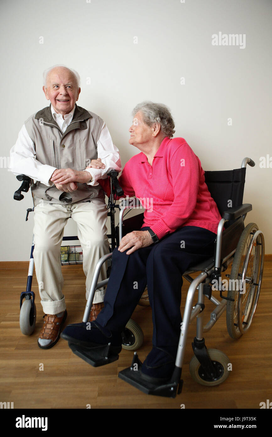 Senior citizen's couple,happily sit,invalid's wheel chair,walking help,arm in arm,people,married couple,senior citizens,couple,old,actively,geriatric care,old care,cohesion,old age,partnership,old people's home,nursing home,disease,health,inside,two,affection,happily, Stock Photo