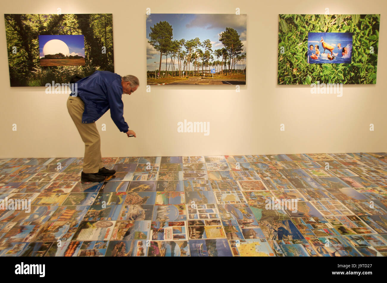 A visitor looks at photos on the floor at the exhibition 'French Bashing' by Michel Houellebecq at the Venus gallery in the Upper East Side in New York, US, 2 June 2017. Houellebecq presented a selection of his artworks for the first time in New York. Photo: Christina Horsten/dpa Stock Photo