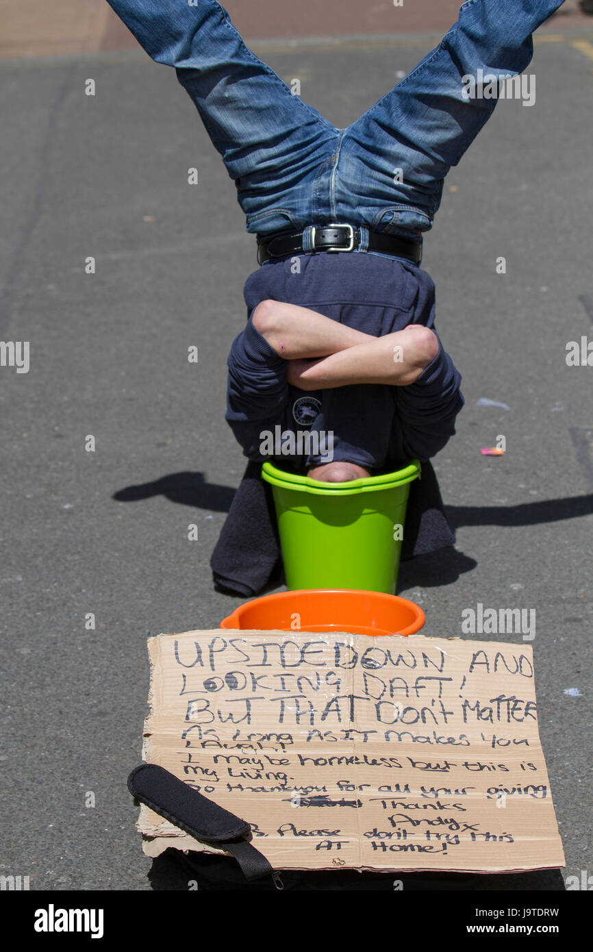 Blackpool, Fylde Coast, Lancashire,   UK Weather.   3rd June, 2017. Holidaymakers head for the resort beach in the warm June sunshine. The holiday season appears to have commenced in this famous north-west seaside resort.  A homeless, unemployed demonstrates  holding a poster and with his head in a bucket. Stock Photo