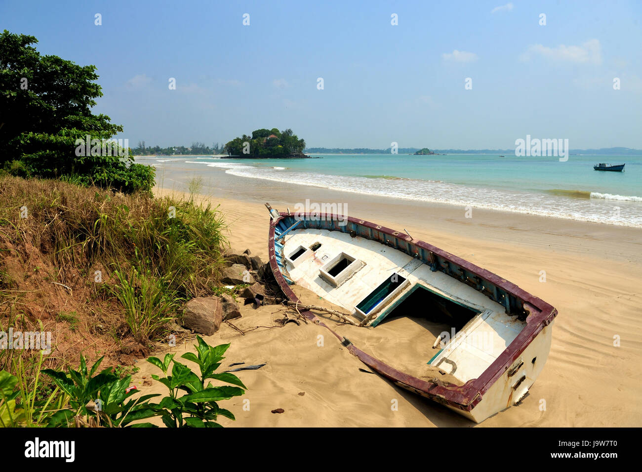 Old yacht stranded on a beach after storms in ocean Stock Photo