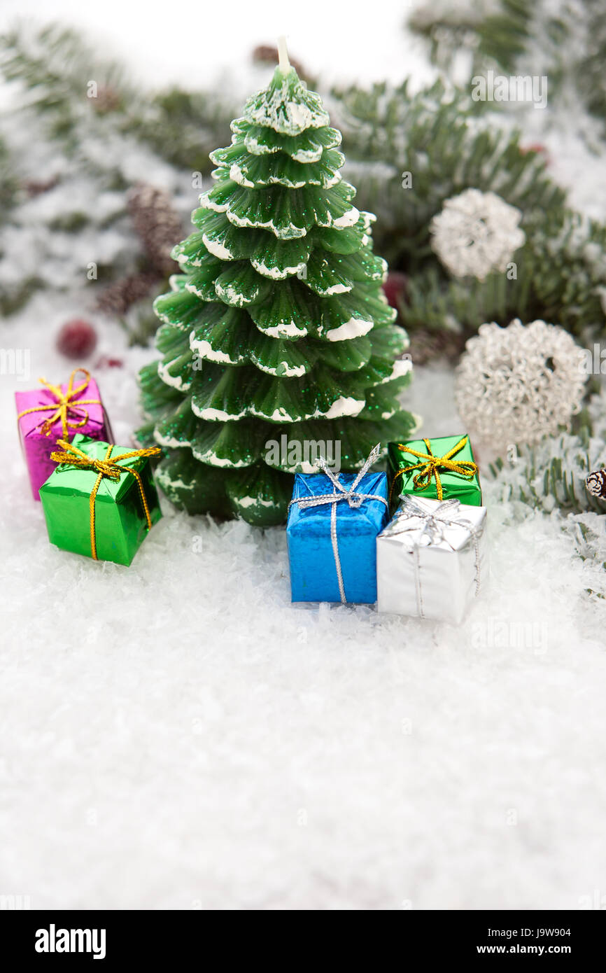 christmas candle in the snow with gift packages Stock Photo