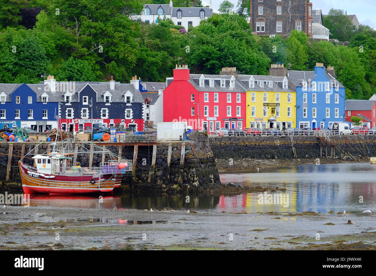 The brightly painted buildings on the waterfront with fishing boats in the harbour, Tobermory, Mull, Scotland Stock Photo