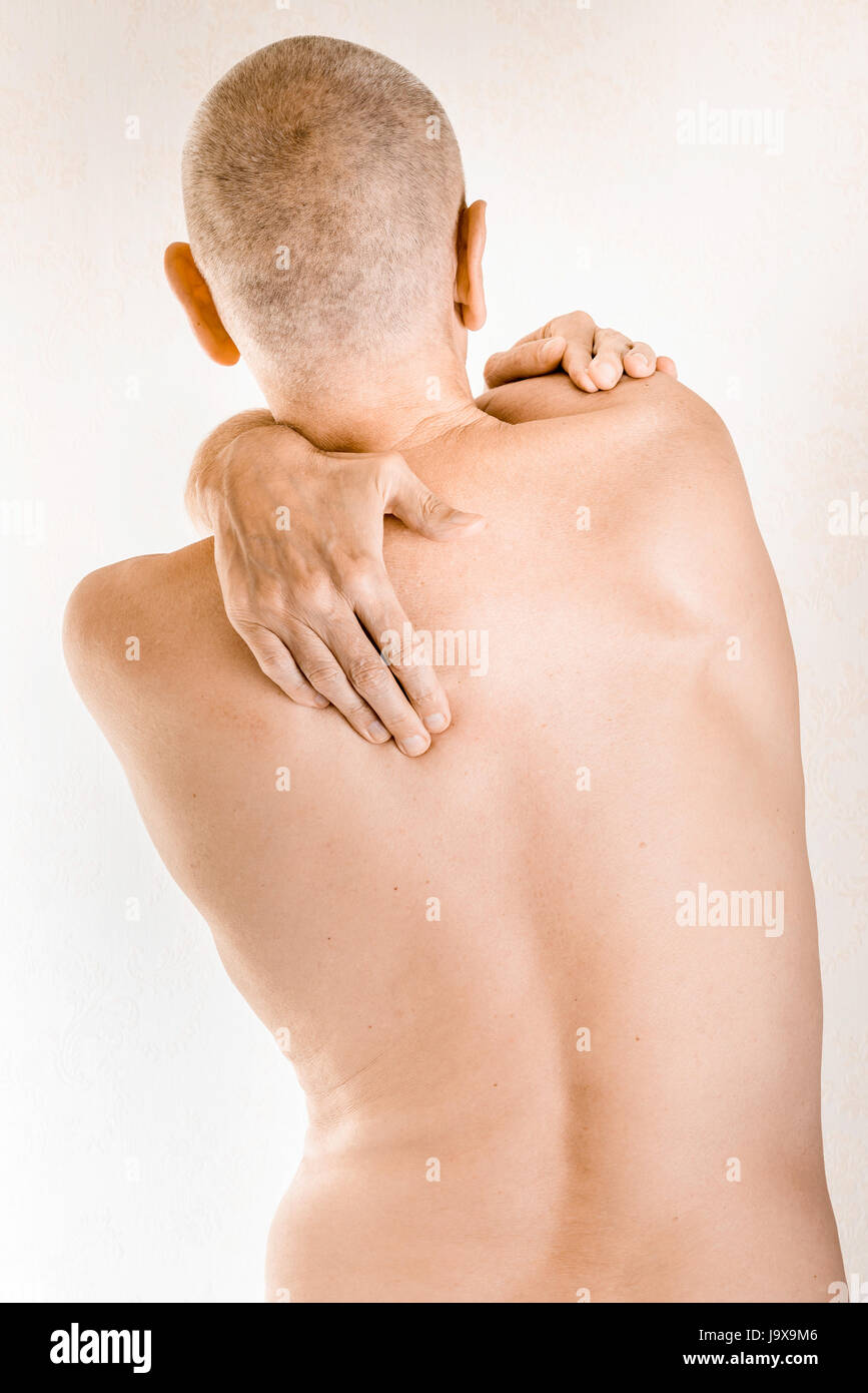 Man massaging his top back, the trapezius muscle, because of a thoracic vertebrae pain due to a displacement of a dorsal vertebra rubbing on a nerve Stock Photo