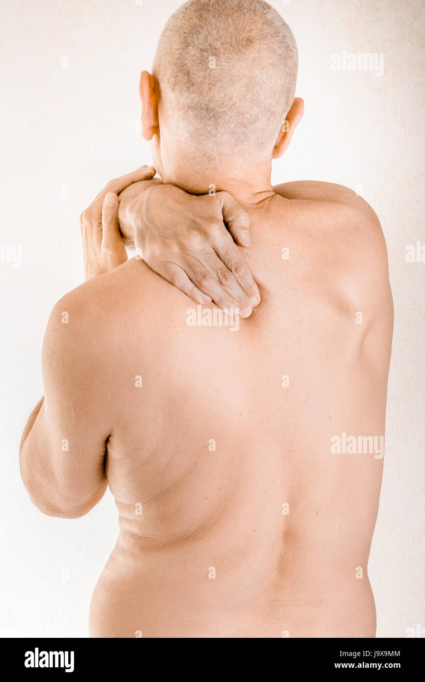 Man massaging his top back, the trapezius muscle, because of a thoracic vertebrae pain due to a displacement of a dorsal vertebra rubbing on a nerve Stock Photo