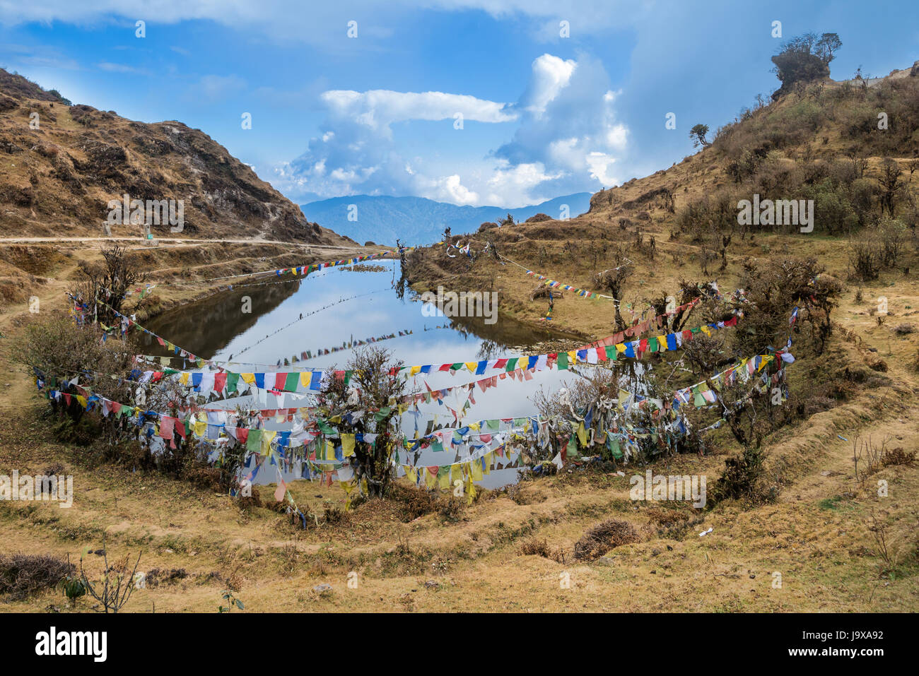 Kala Pokhri, the Black Water Pond with multi-colored prayer flags flung across, on the trekking route to Sandakphu inside the Singalila National Park, Stock Photo