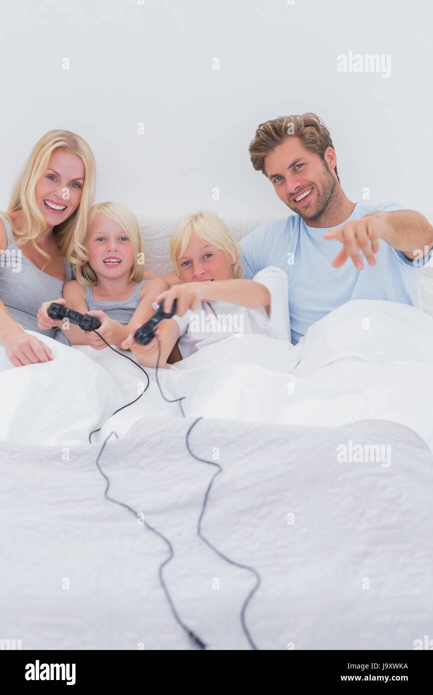 Cheerful family playing video games in bed Stock Photo Alamy