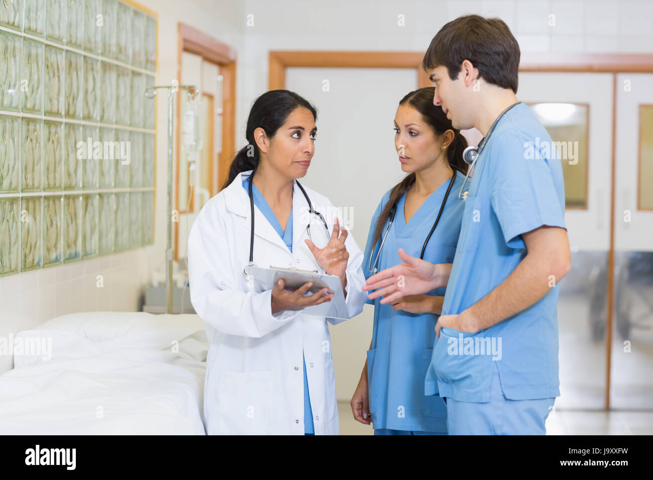 Female doctor talking to a male and a female nurse in a hospital ...