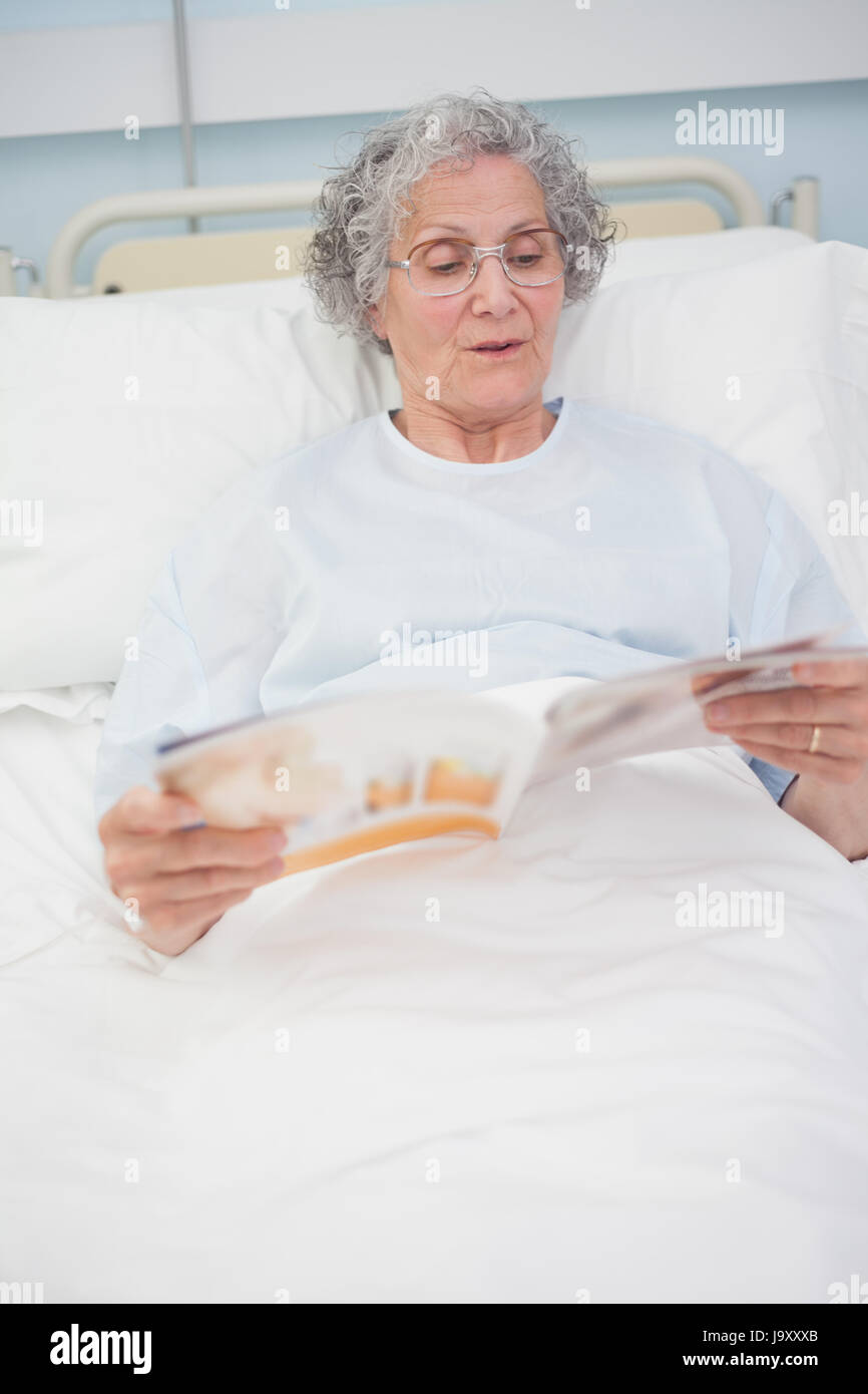 Patient reading a magazine on her bed in hospital ward Stock Photo Alamy
