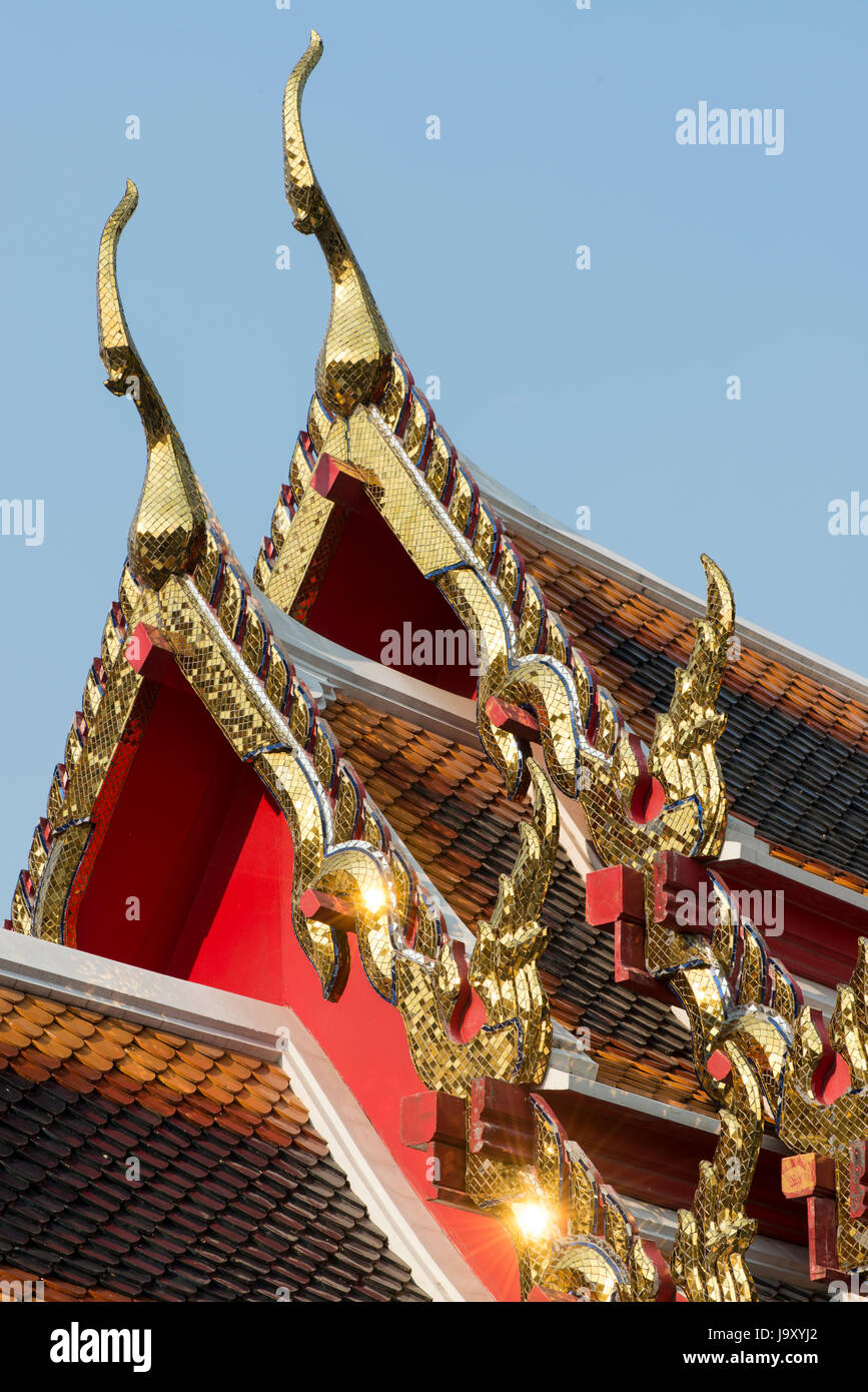 Intricate coloured glass mosaics adorn the eaves and finials of the roof to a shrine at Wat Pho, Bangkok, Thailand Stock Photo