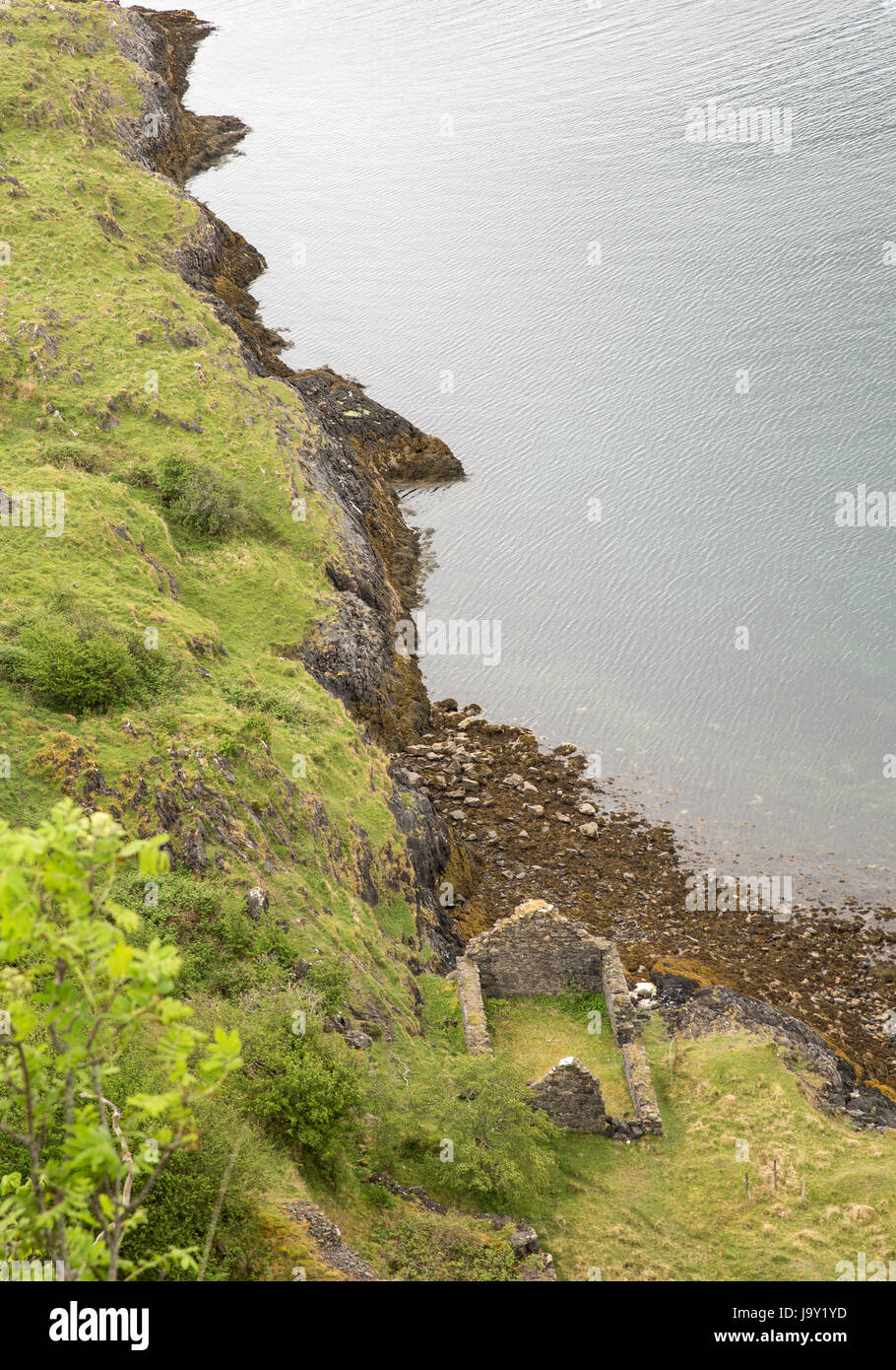 Seashore and calm sea on the coast of Lismore in Scotland, with old ruined house in the foreground Stock Photo