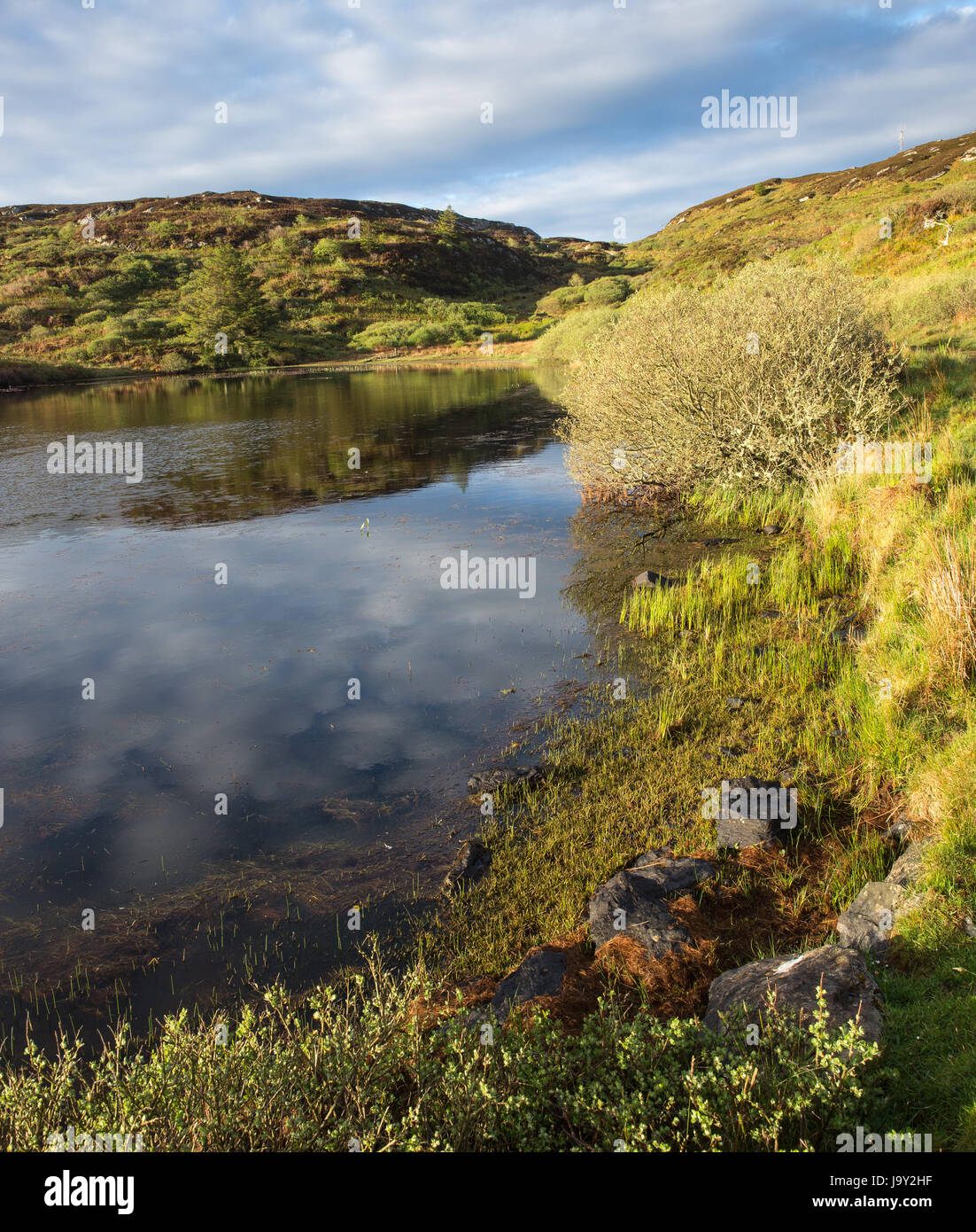 Small loch on the island of Colonsay in Scotland taken early in the morning with reflection of clouds in the water Stock Photo